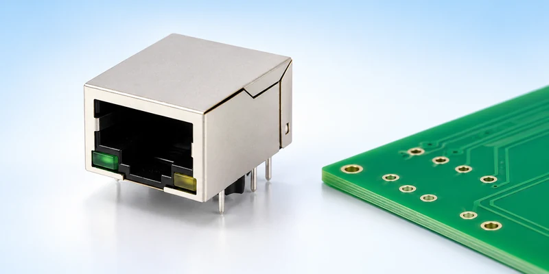 Single-port through-hole RJ45 jack beside an unpopulated PCB with plated holes